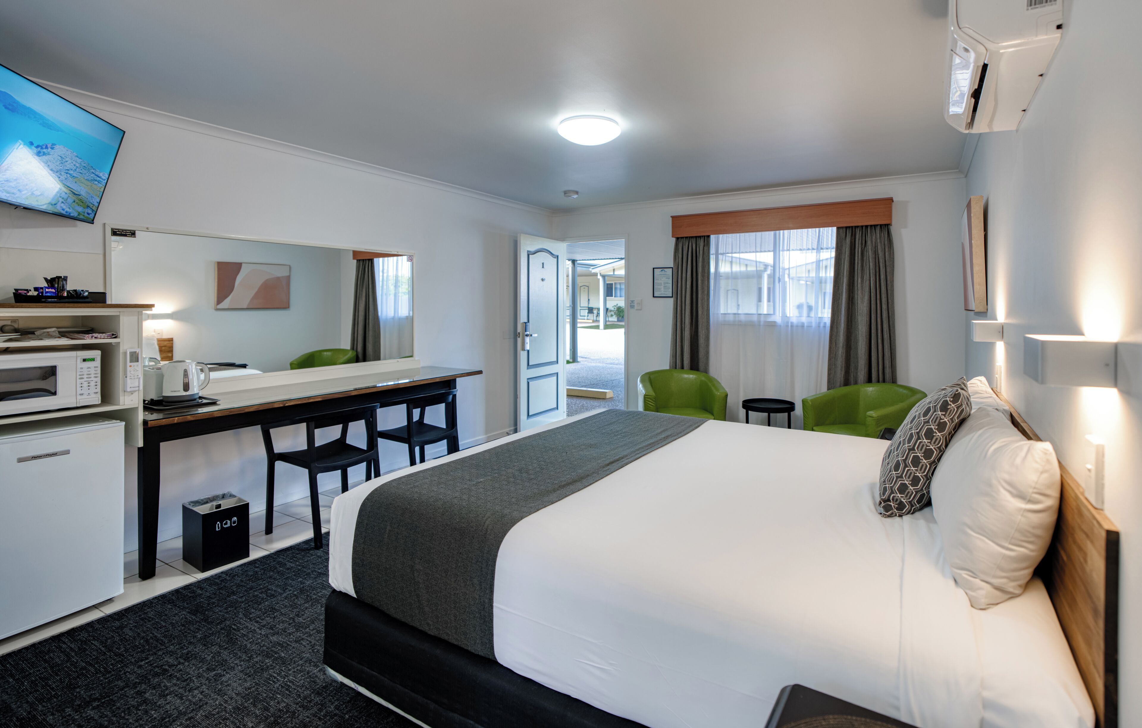 Una habitación de hotel con cama, escritorio, silla, televisor y microondas.