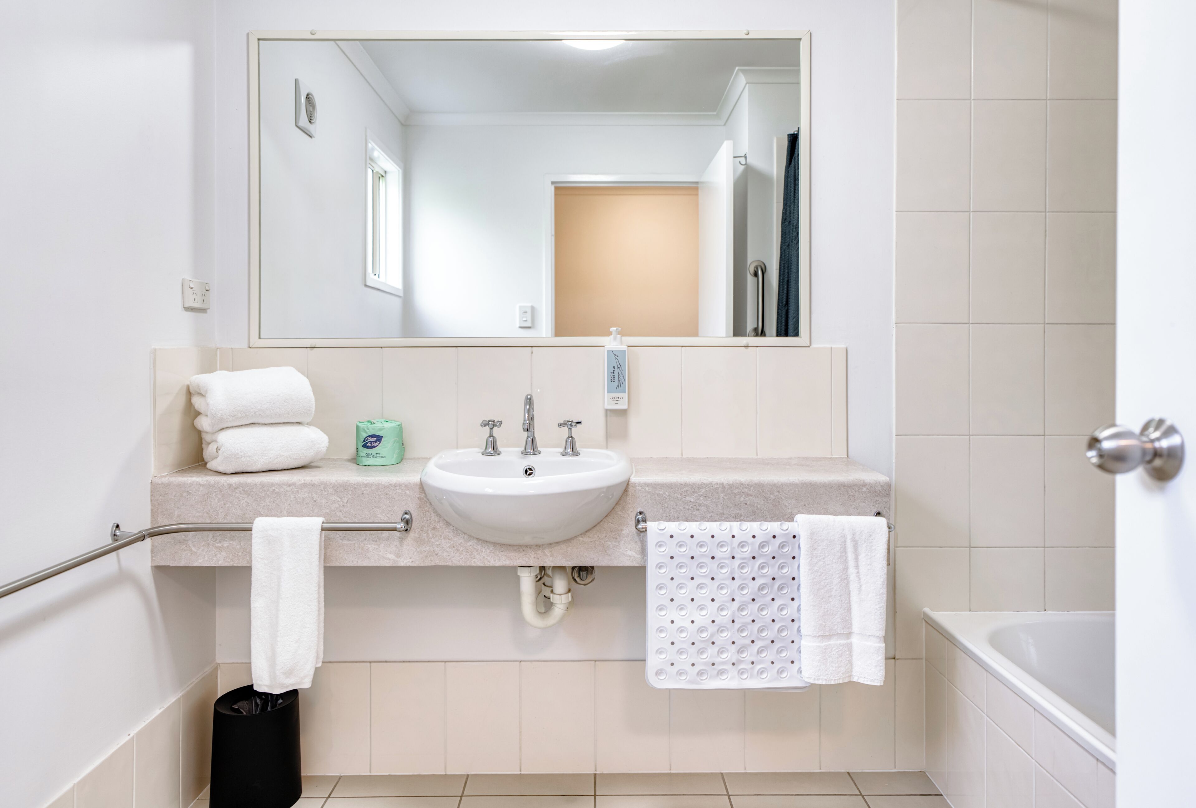 A bathroom with a sink, mirror, towel rack, and a bathtub.
