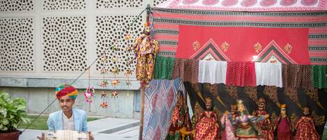 A person playing a drum, a tent with colorful fabrics, and a decorative wall with intricate patterns.