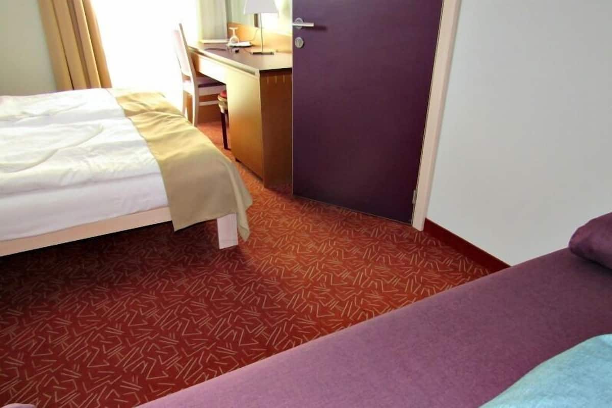 Ein Hotelzimmer mit Bett, Schreibtisch und Tür.