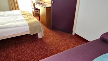 Ein Hotelzimmer mit Bett, Schreibtisch und Tür.
