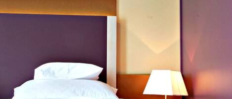Una habitación de hotel con una cama, un cuadro en la pared y una lámpara.