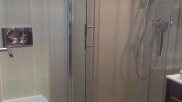 A bathroom with a glass-enclosed shower, a toilet, and a sink.