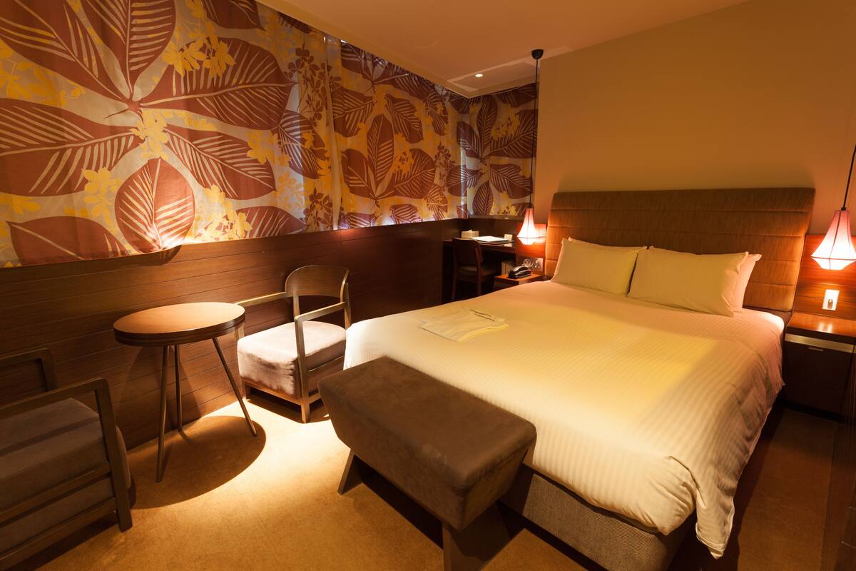Une chambre d’hôtel avec un lit, un bureau, une chaise et une petite table.