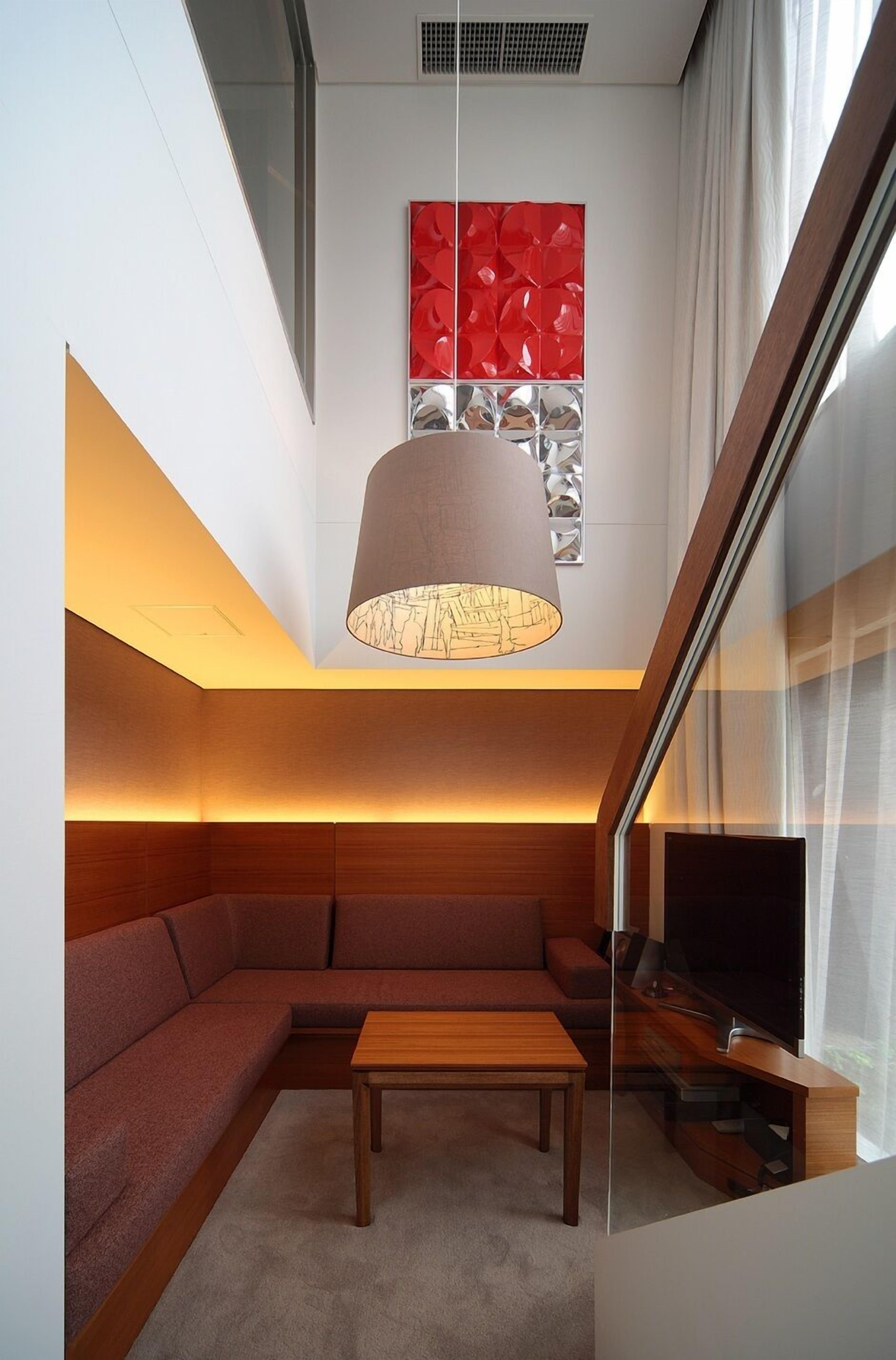 A modern living room with a sofa, a wooden coffee table, a TV, and a unique ceiling light fixture.