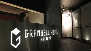 Una entrada moderna de hotel con un llamativo letrero iluminado que dice "GRANBELL HOTEL SHIBUYA".