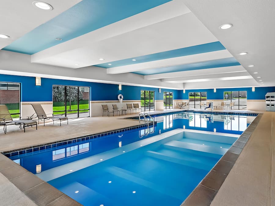Una amplia piscina interior con agua cristalina, rodeada de sillones de descanso y una zona de estar cubierta.