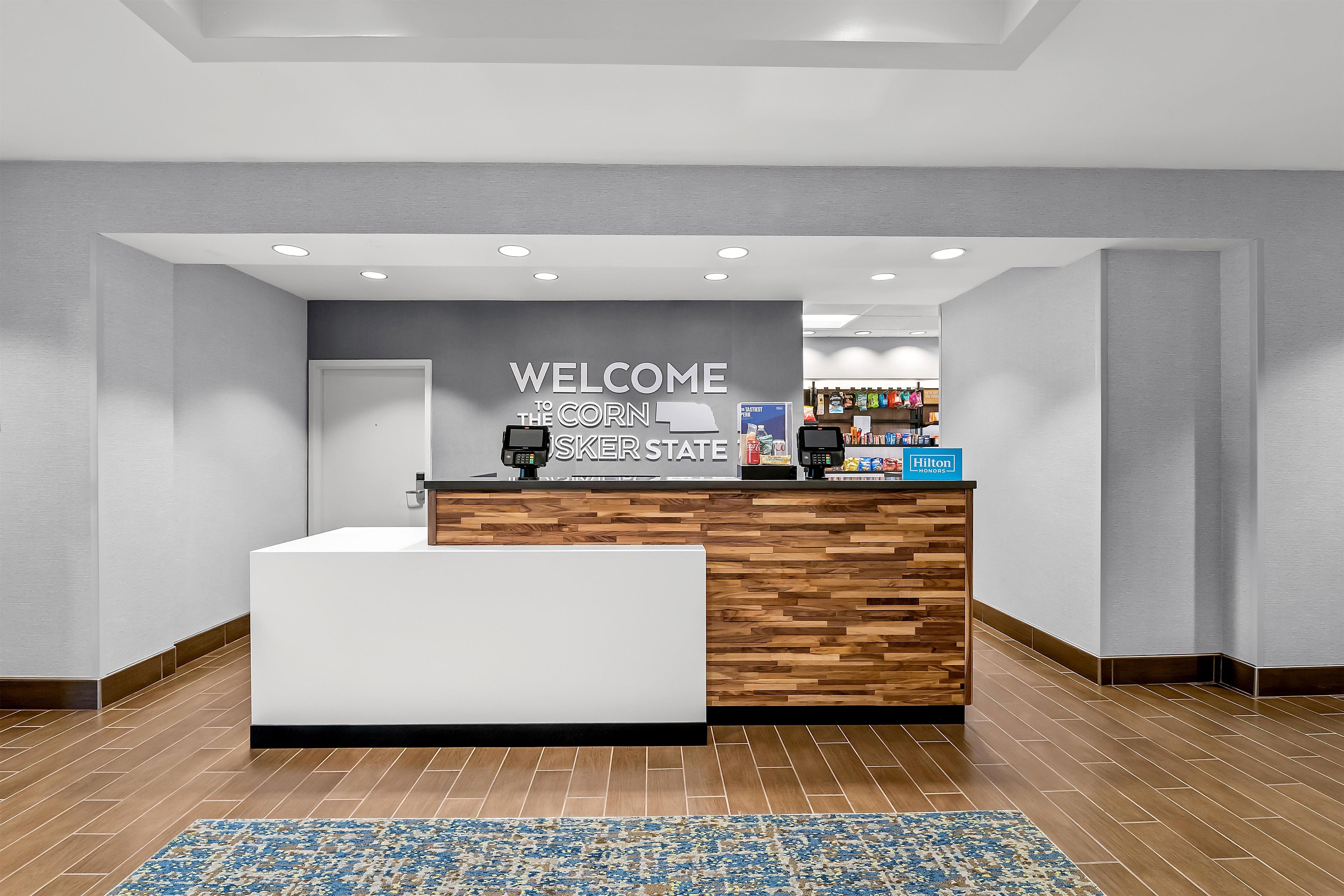 A reception area with a 'WELCOME TO THE CORN' sign, a wooden counter, and a tiled floor.