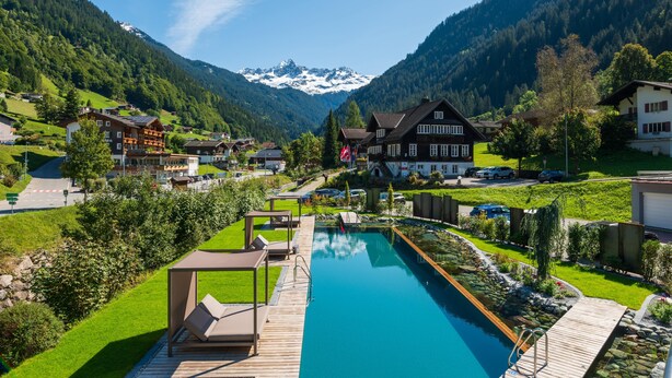 A resort with a swimming pool, wooden deck, and mountain views. - Hotel Bergkristall (Silbertal)