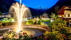 A fountain in a circular pool with a mountain backdrop. - Hotel Bergkristall (Silbertal)