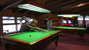 A pool table with a green felt surface, wooden frame, and a red carpeted floor. - Ski Rider Hotel (Wilsons Valley)