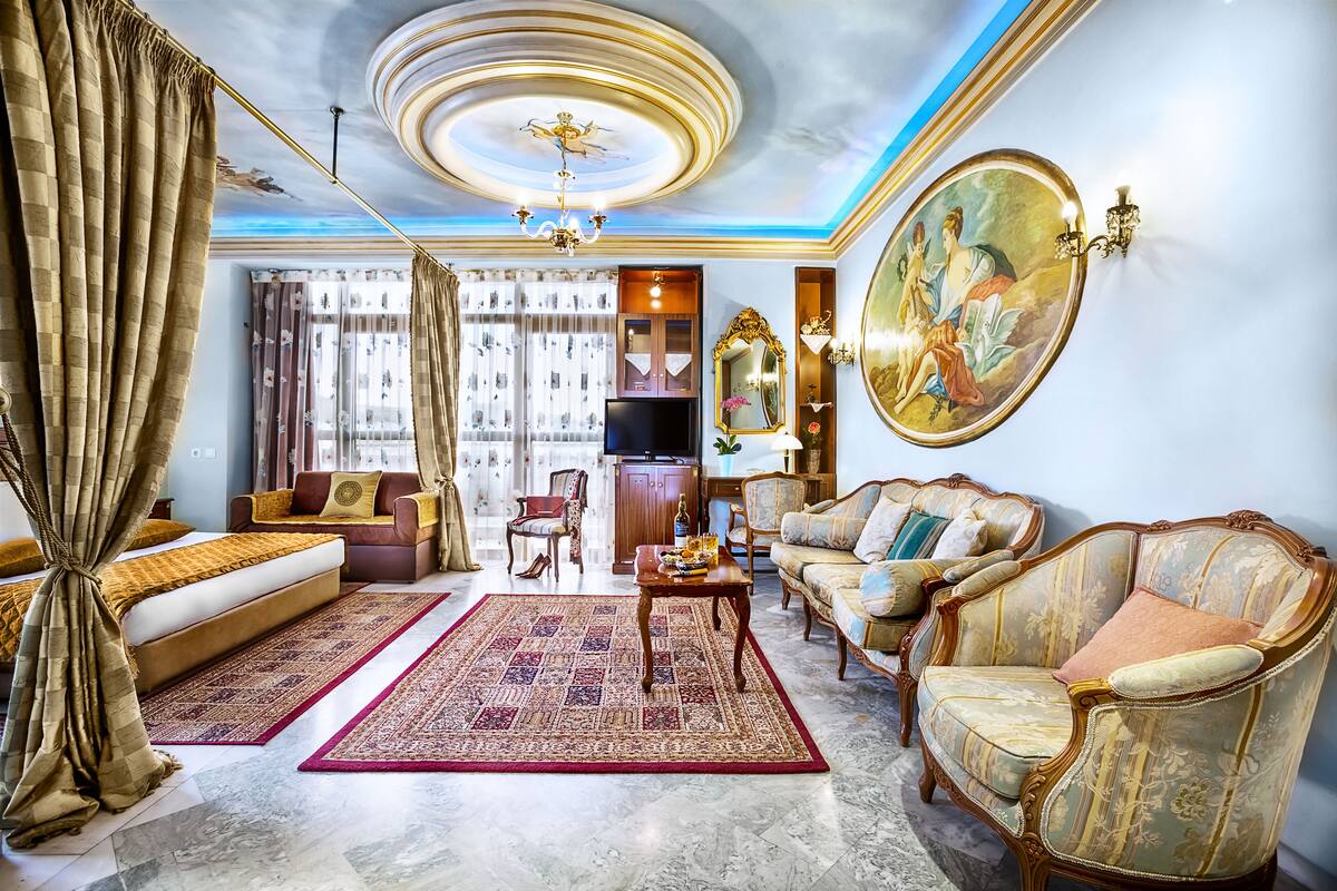 A spacious living room with a sofa, armchairs, a coffee table, and a TV.