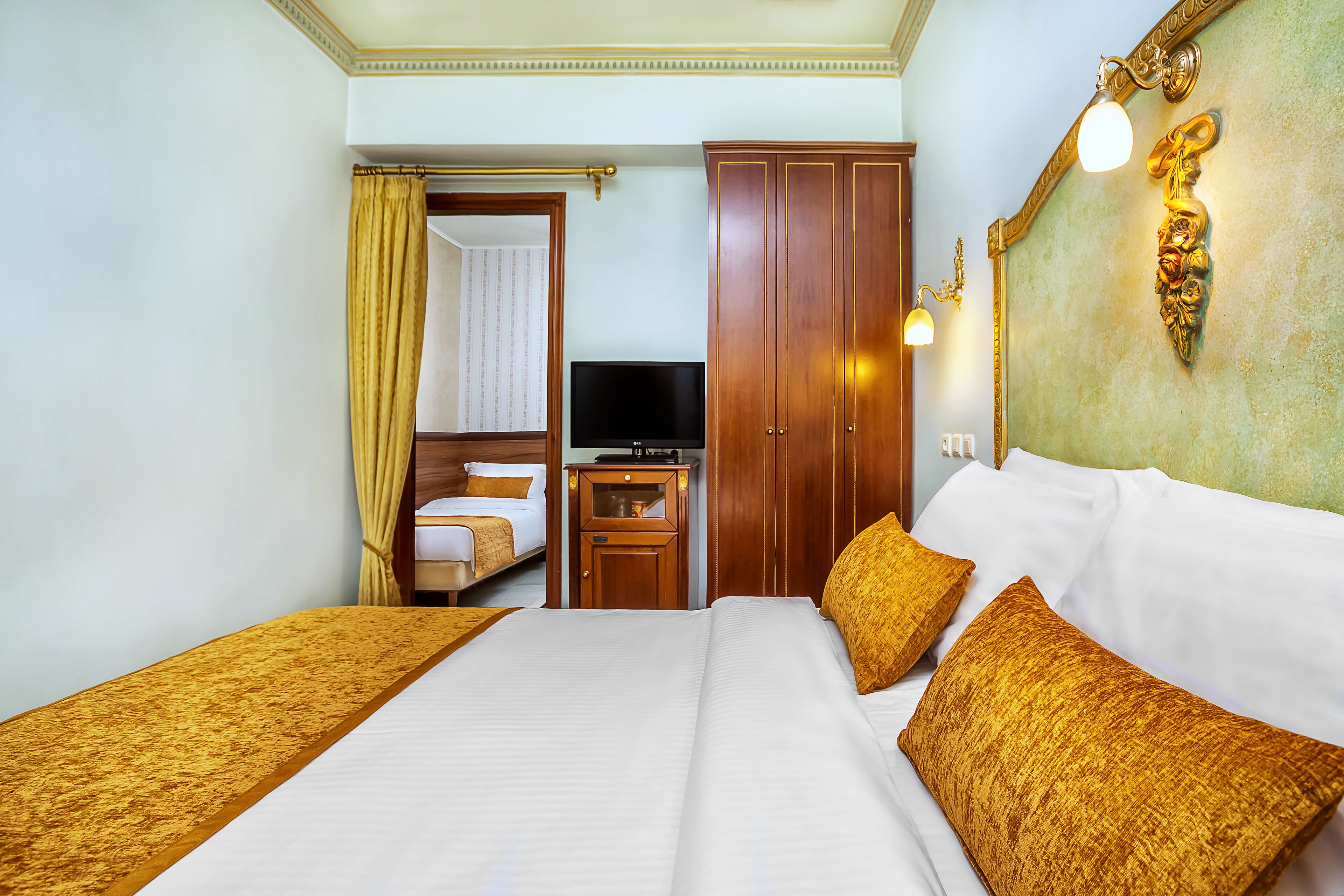 Une chambre d’hôtel avec un grand lit, une télévision, une armoire et un bureau avec une lampe.