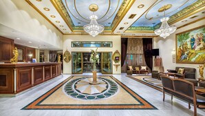 A luxurious lobby with a grand reception desk, a central chandelier, and a large mural on the wall. - Imperial Palace Classical Hotel Thessaloniki (Thessaloniki)