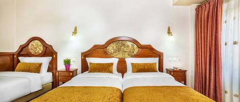 A hotel room with two beds, a wooden headboard with a circular design, a nightstand with a lamp, and a red curtain.