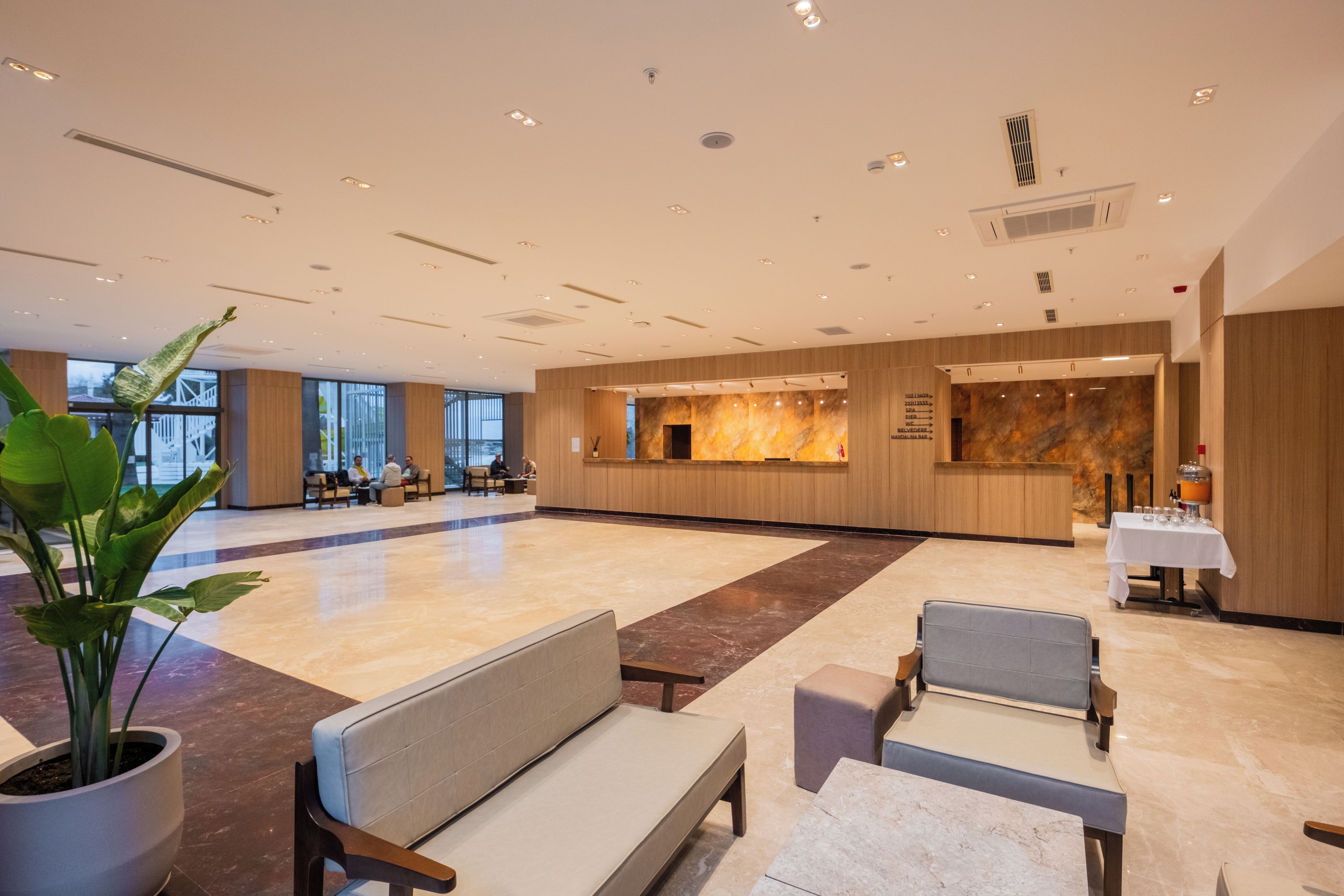 Eine geräumige Lobby mit einer Rezeption, einer Sitzecke und einer großen Pflanze.