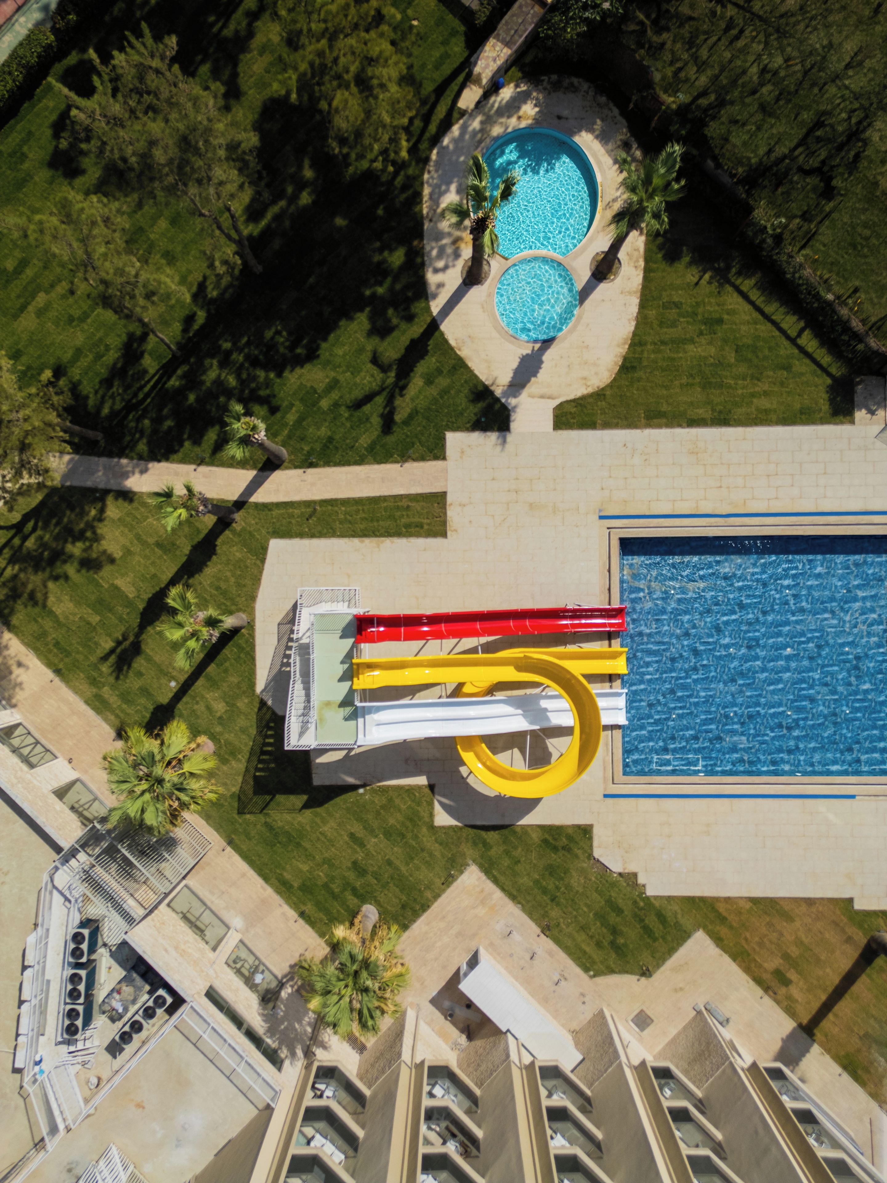Ein Luftbild eines Hotels mit Schwimmbad, Wasserrutsche und Dachterrasse.