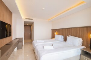 Una habitación de hotel con una cama grande, un televisor, un cabecero de madera y una lámpara de noche.