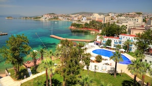 A resort with a swimming pool, palm trees, and a view of the sea.