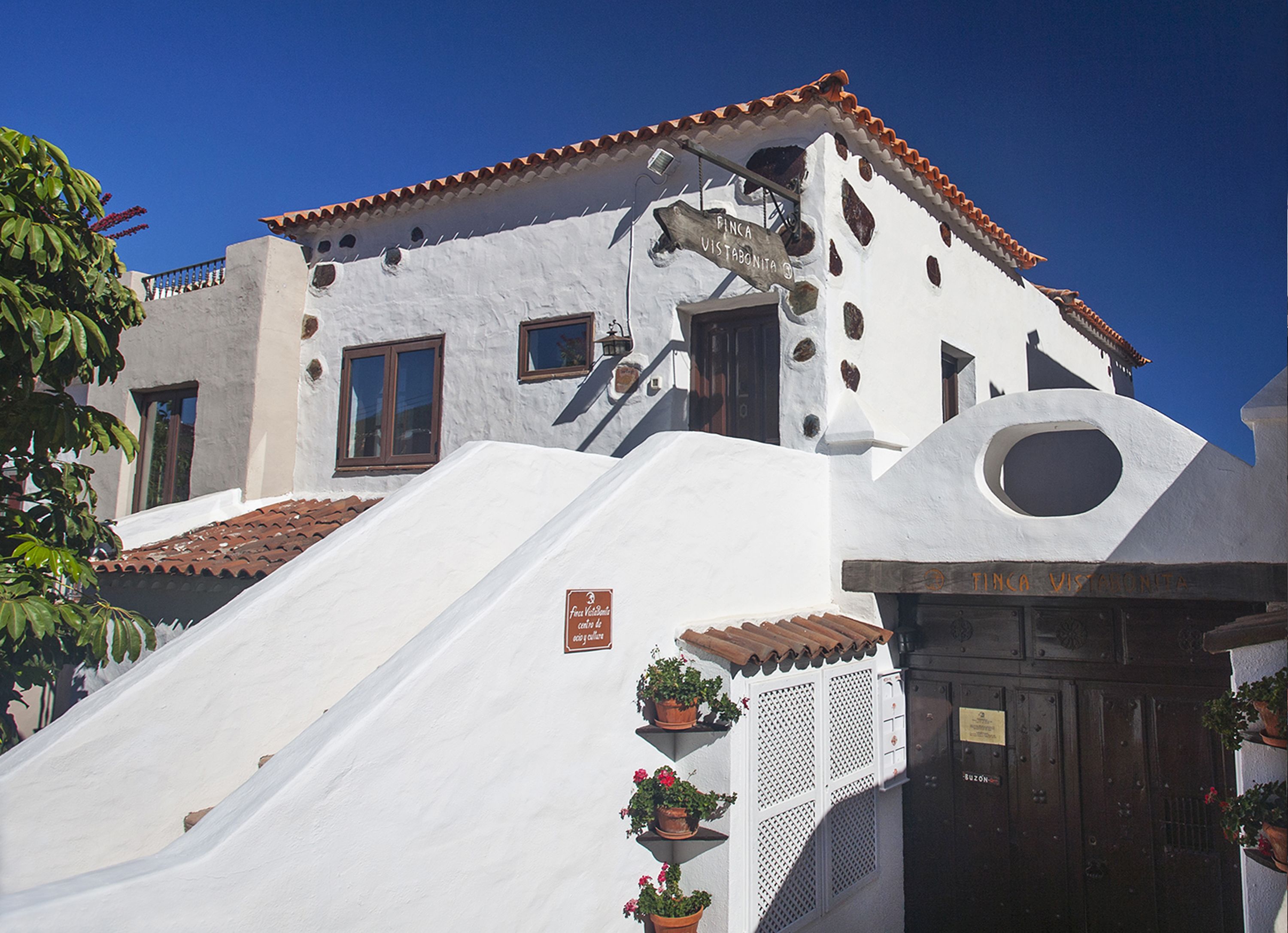 A white building with a sloped roof and a sign reading "Finca Vista Monta".