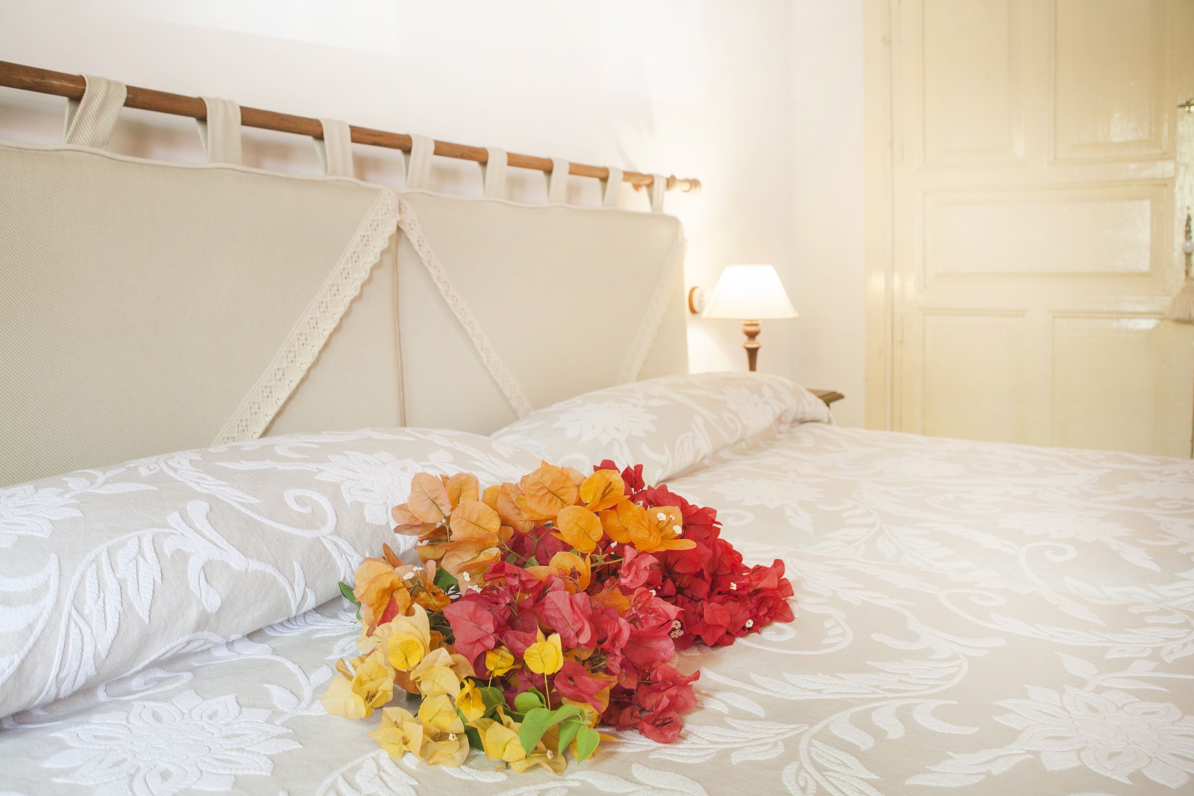 A neatly made bed with a floral arrangement on the bedspread.