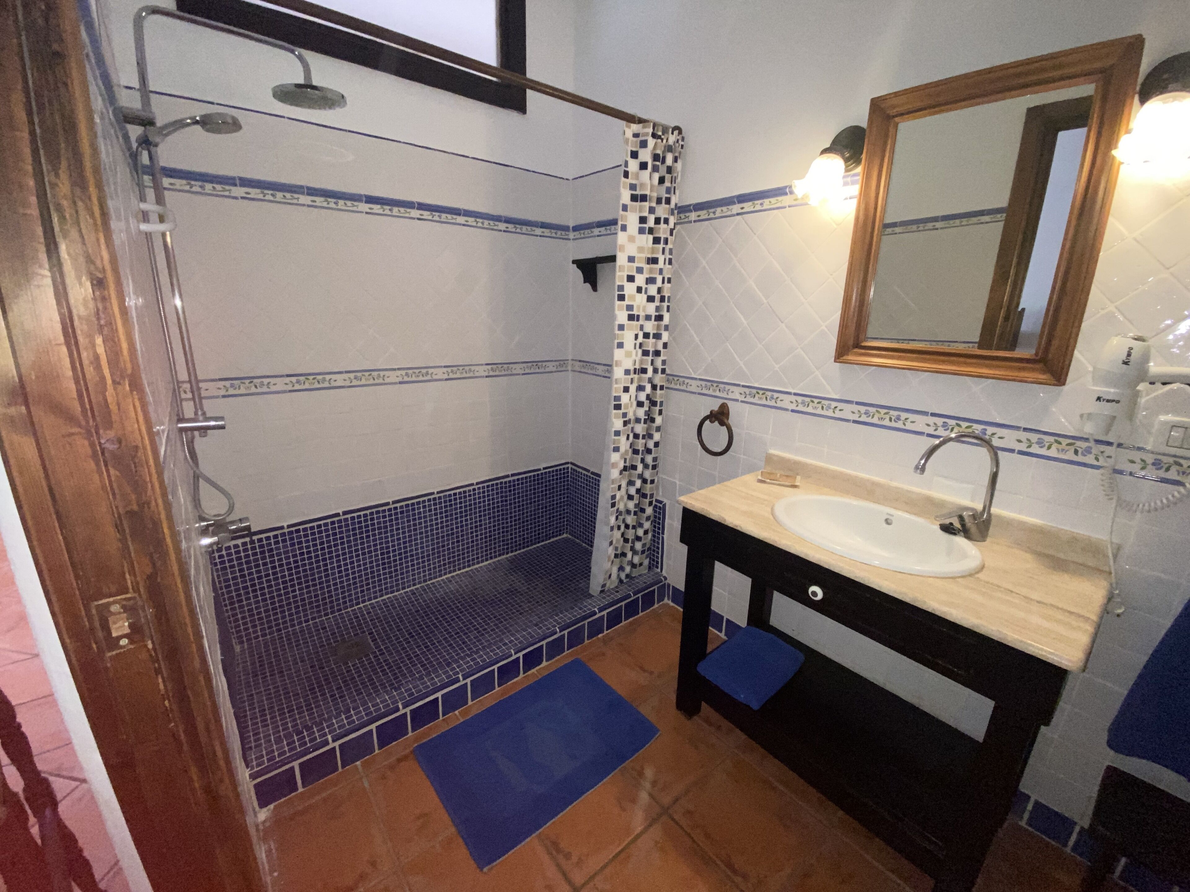 A bathroom with a shower, a sink, a mirror, and a towel rack.