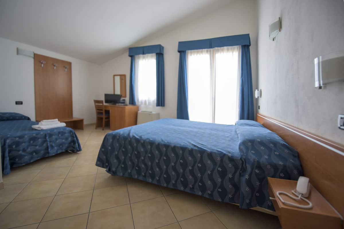A hotel room with two beds, a desk, and a chair.