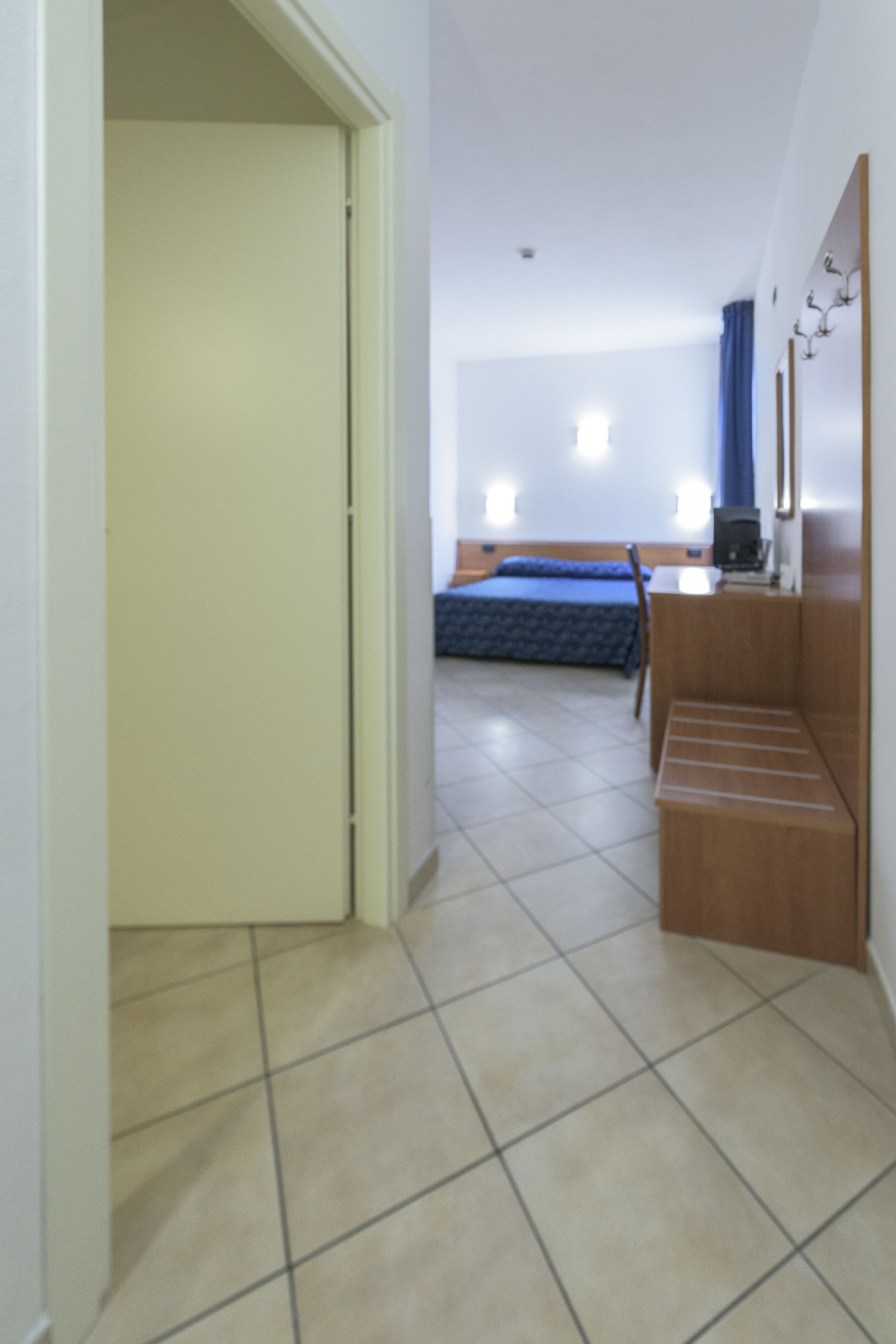 A hotel room with a bed, a desk, and a chair.