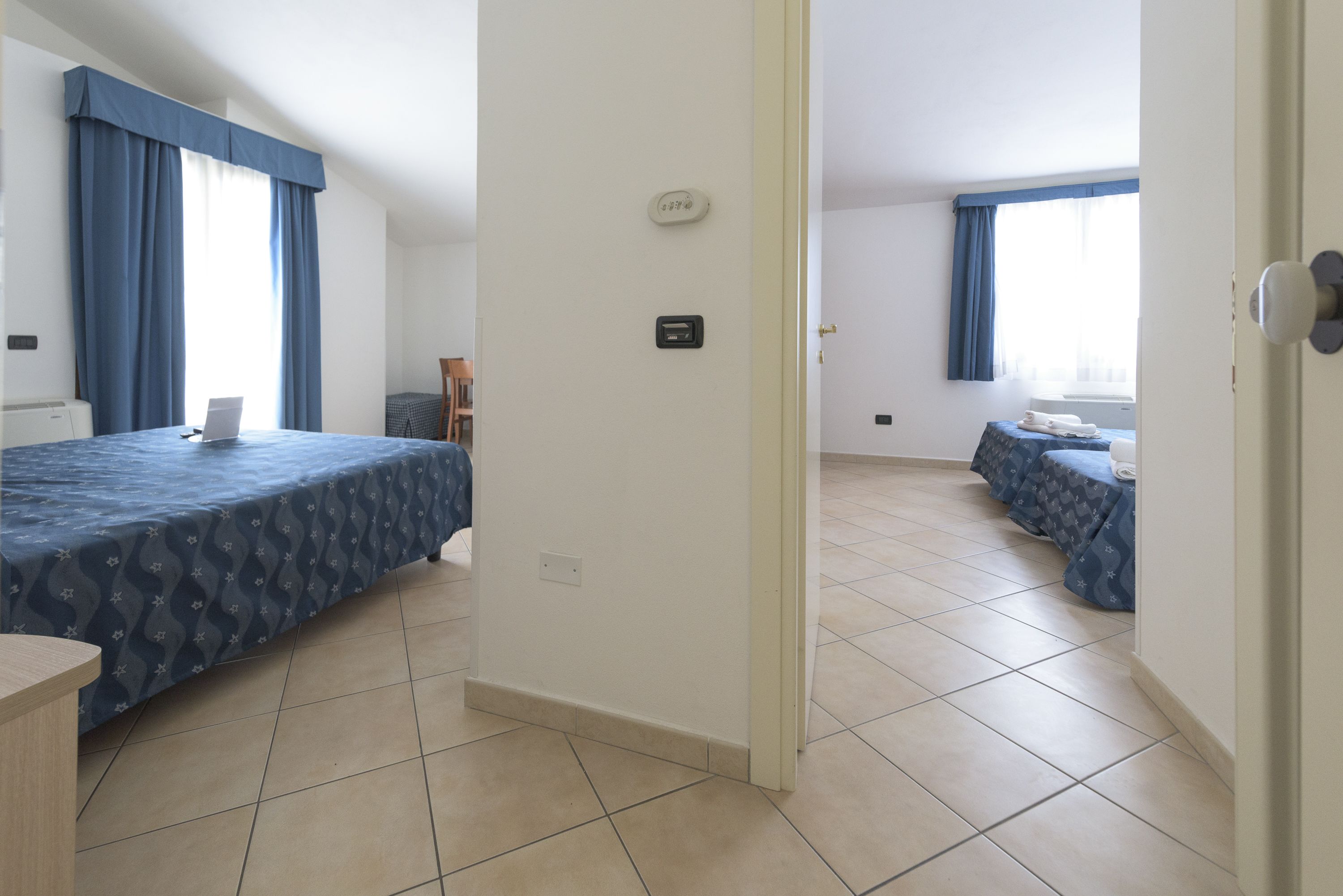A hotel room with two beds, a desk, and a chair.