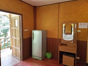 A compact room with a Samsung refrigerator, a wooden vanity with a mirror, and a green trash bin. - Haad Yao Sunset Bungalow (Ko Pha-ngan)