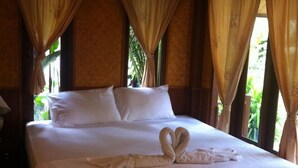 A large bed with white linens, two pillows, and a heart-shaped towel arrangement. - Haad Yao Sunset Bungalow (Ko Pha-ngan)