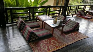 A wooden deck with a sofa set, a table, and a patterned rug. - Haad Yao Sunset Bungalow (Ko Pha-ngan)