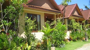 A row of bungalow-style houses with pitched roofs, surrounded by lush tropical vegetation. - Haad Yao Sunset Bungalow (Ko Pha-ngan)