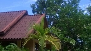 A building with a red roof, surrounded by lush greenery and palm trees. - Haad Yao Sunset Bungalow (Ko Pha-ngan)
