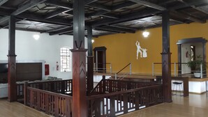 A spacious room with high ceilings, wooden beams, a stage, and a seating area with a television. - Hara Palace Hotel (Curitiba)