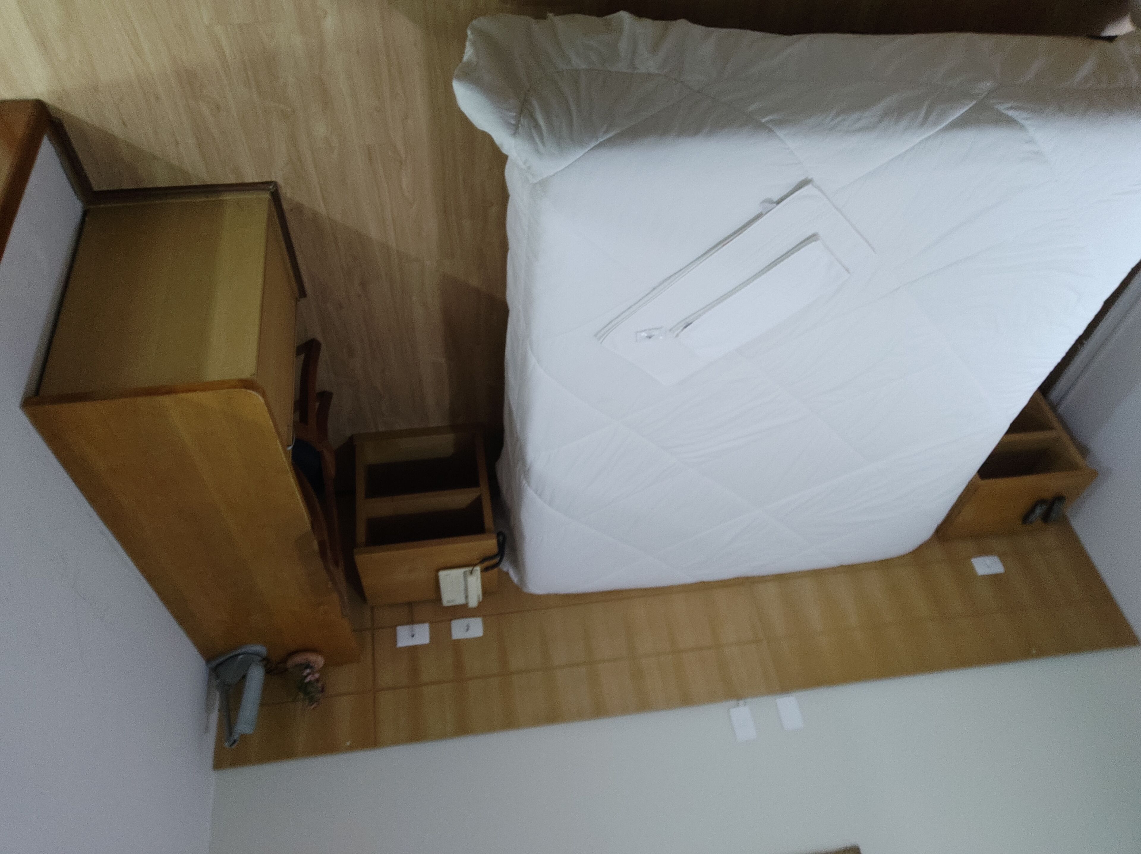 A compact room with a bed, a wooden dresser, and a small table.