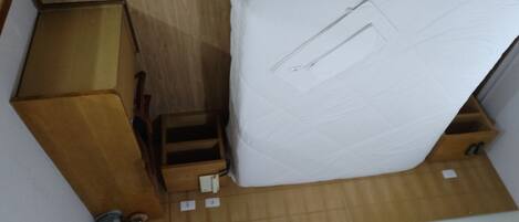 A compact room with a bed, a wooden dresser, and a small table.