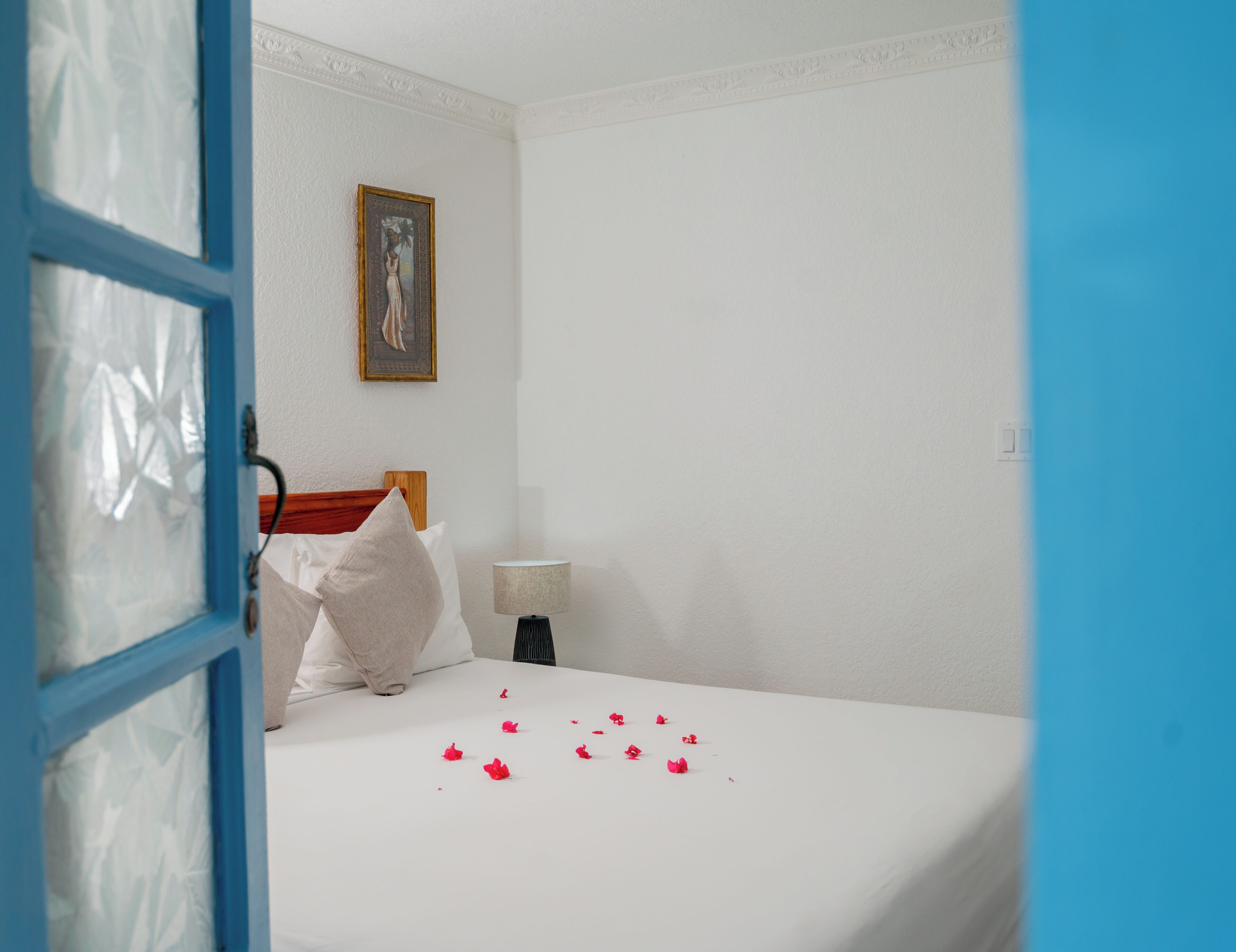 A hotel room with a bed, a nightstand, a lamp, and a painting on the wall.