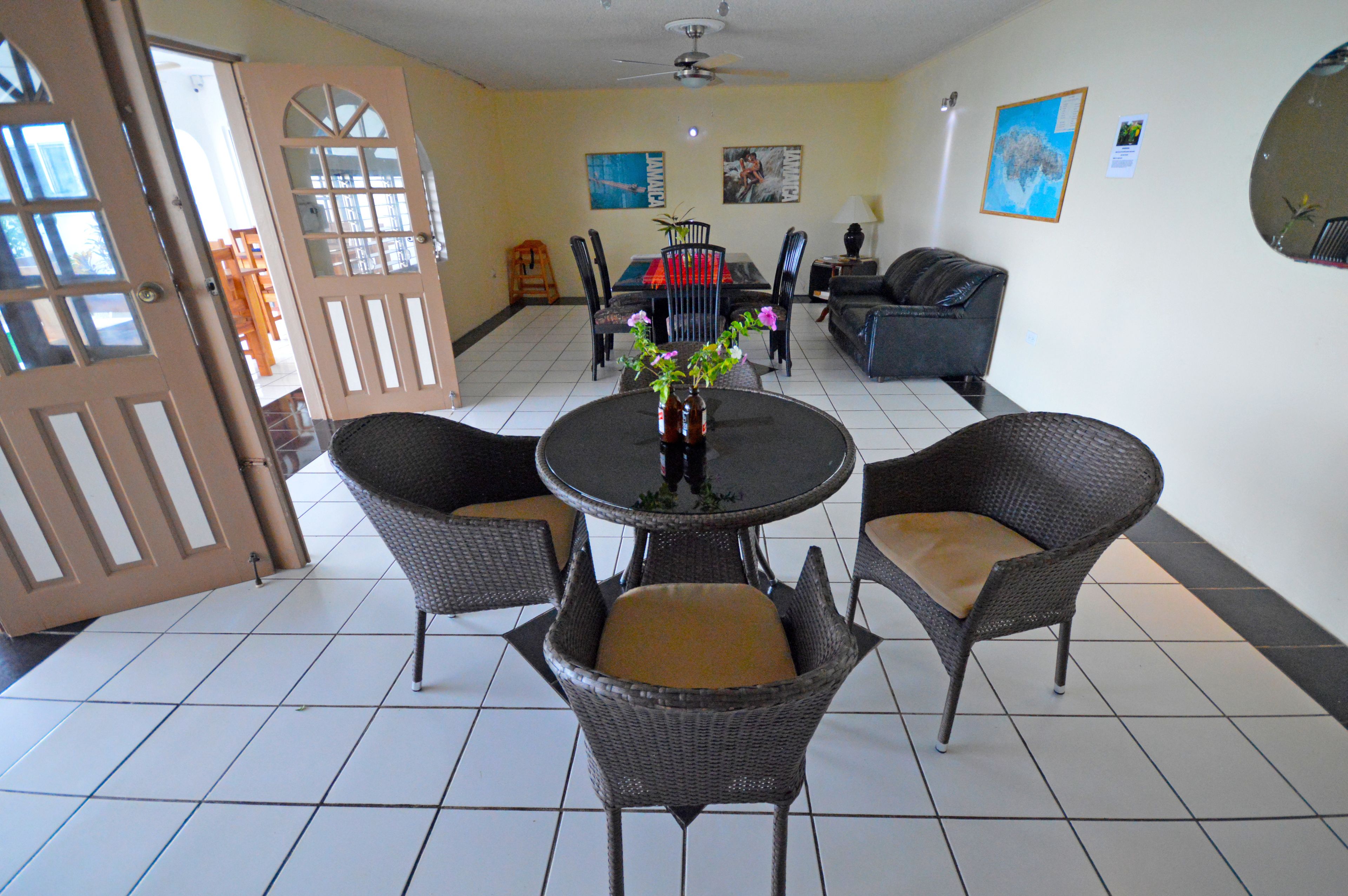 Un comedor con una mesa redonda, cuatro sillas de mimbre y un florero con flores.