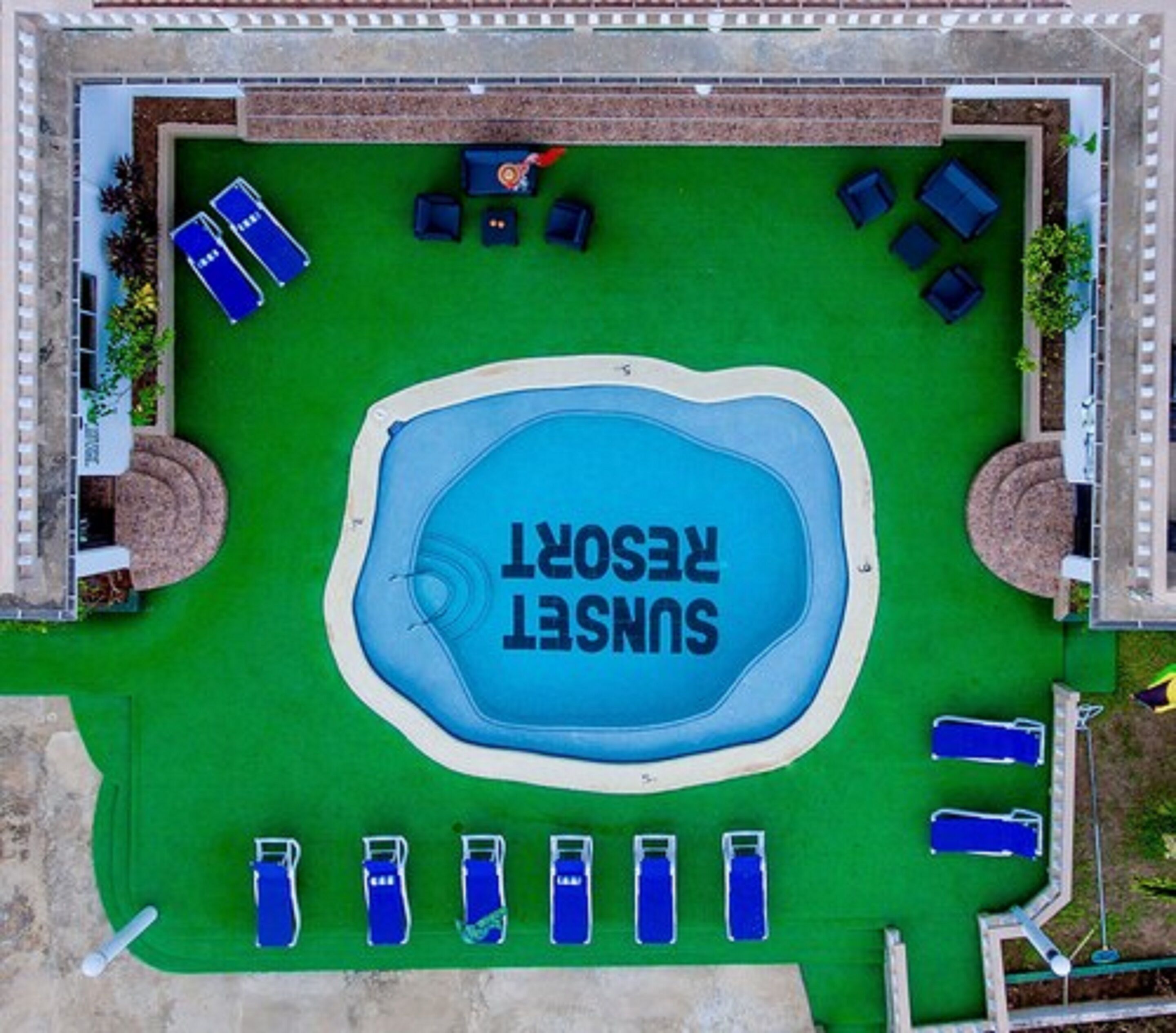 Vista aérea de um resort com uma piscina central identificada como 