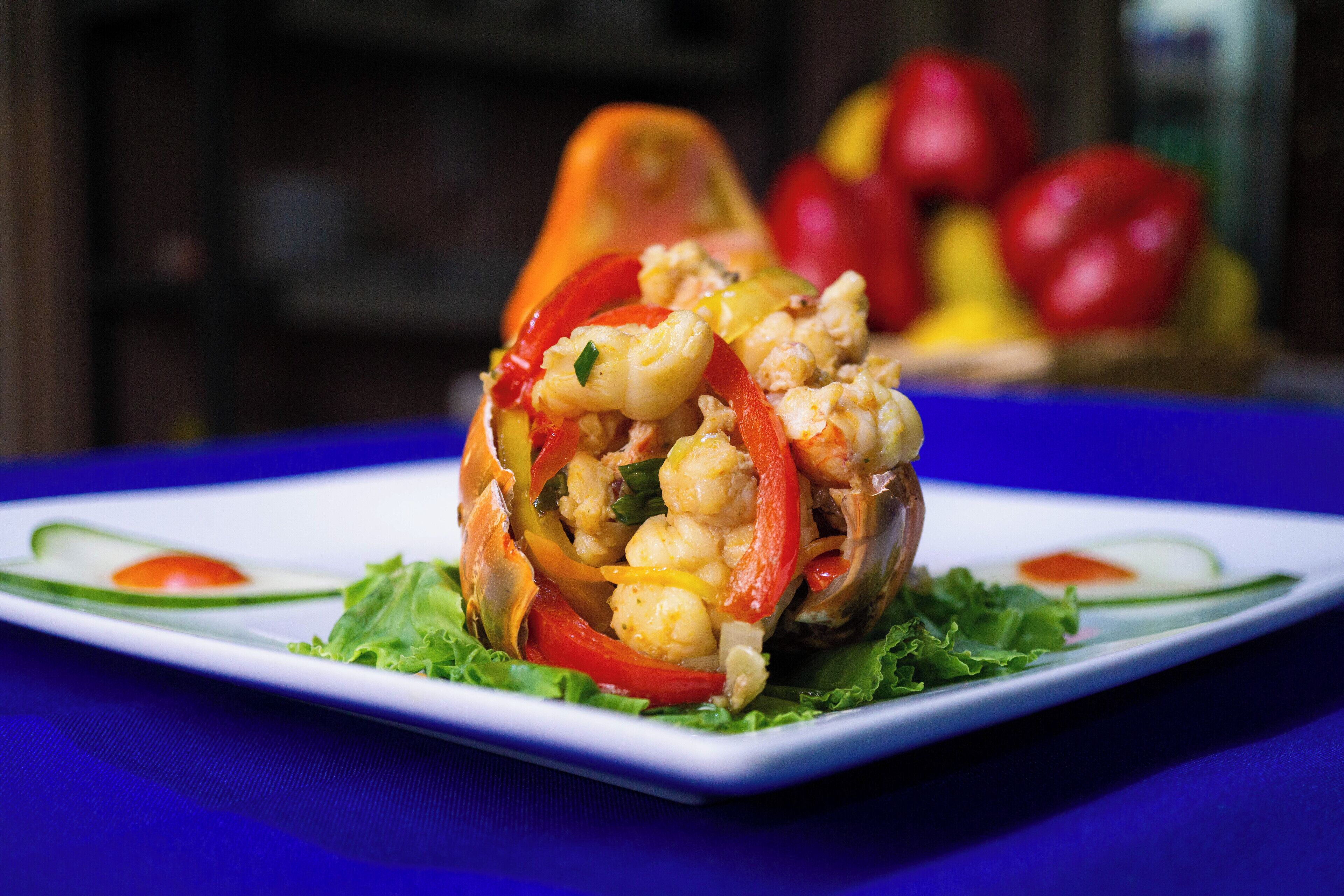 A dish of shrimp and vegetables on a white plate with a blue tablecloth.
