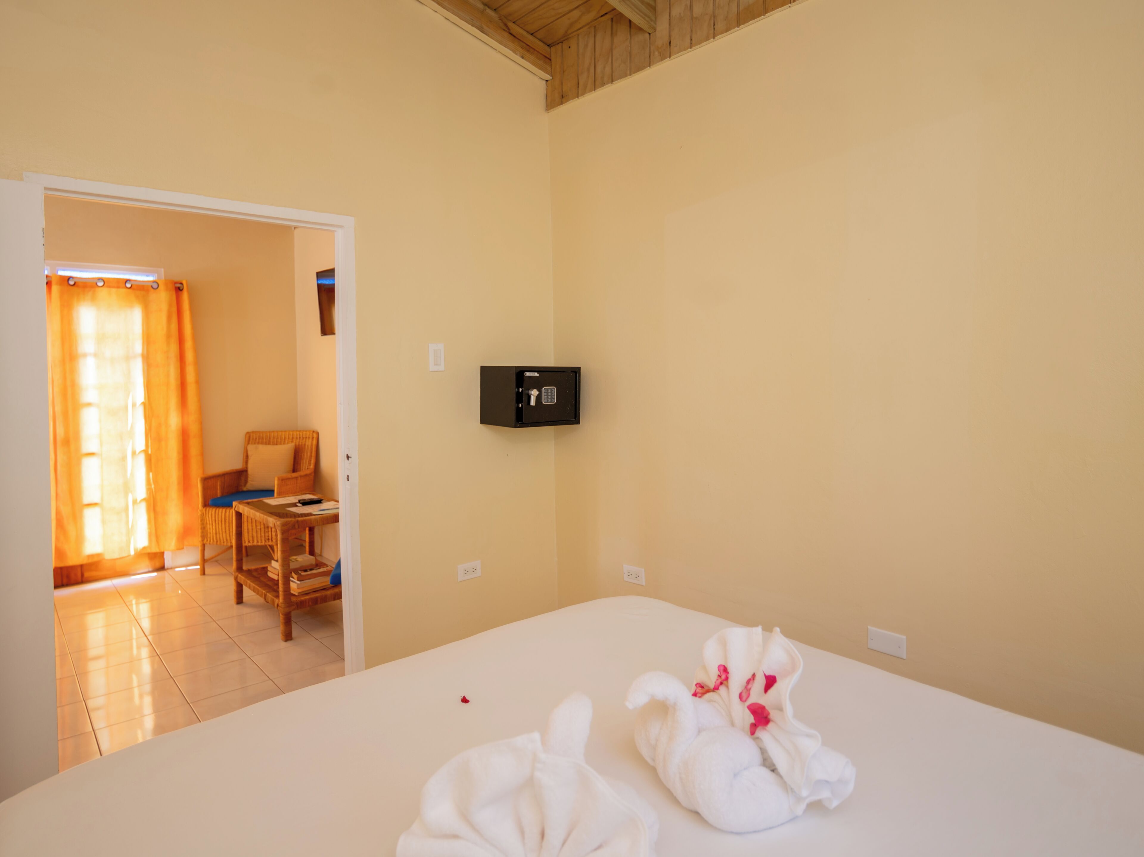 Une chambre d’hôtel avec un lit, un coffre-fort et une vue sur une autre chambre qui contient une chaise et une table.