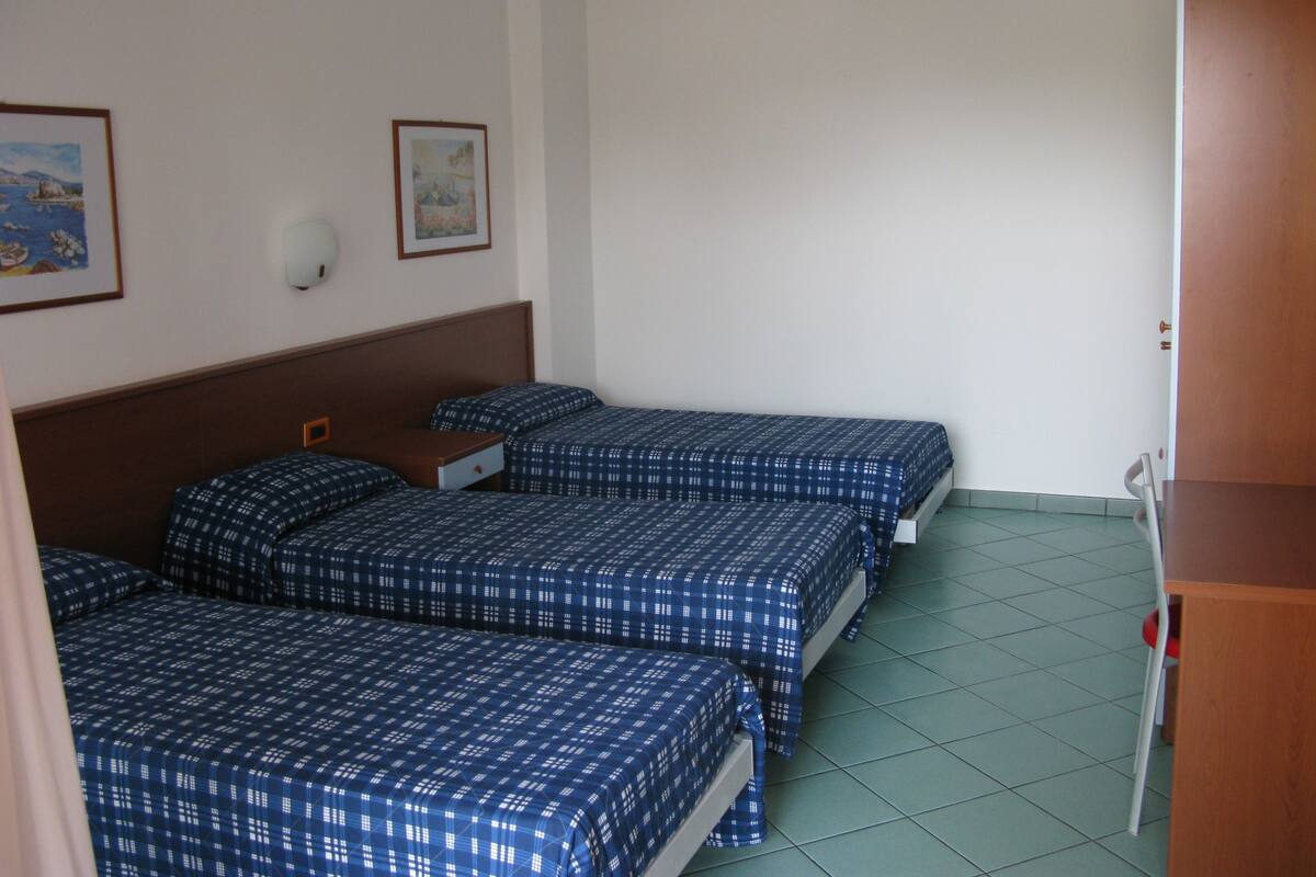 Una habitación con dos camas, cabecera de madera, una mesita y aire acondicionado de pared.
