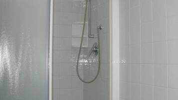 A bathroom with a glass shower enclosure, a white sink, and blue-tiled walls.