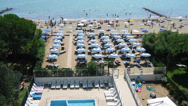 A beachside hotel with a swimming pool, sun loungers, and umbrellas. - Residence Florida (Caorle)