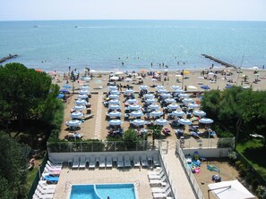 A beachside hotel with a swimming pool, sun loungers, and umbrellas. - Residence Florida (Caorle)