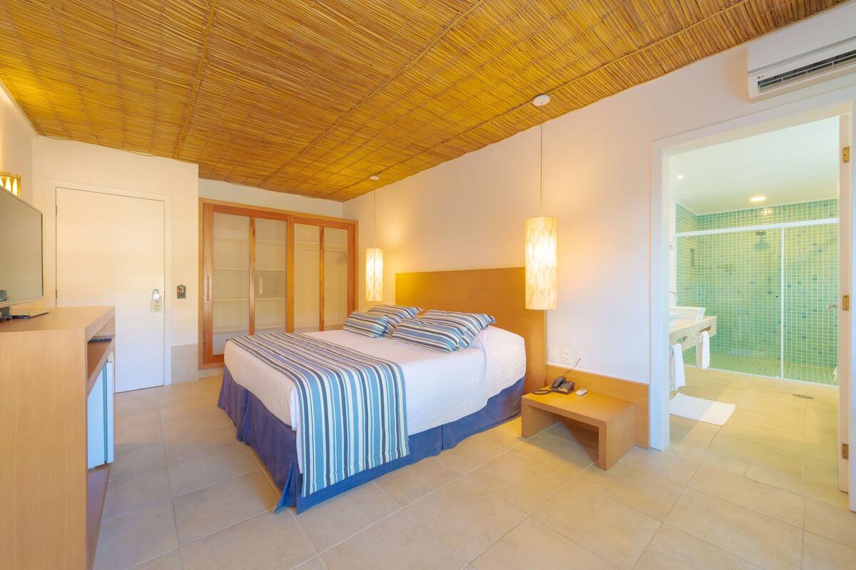 A bedroom with a bed, bedside table, and a bathroom with a shower.