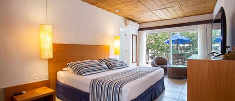 Una habitación de hotel con cama, mesita de noche y vistas al exterior.