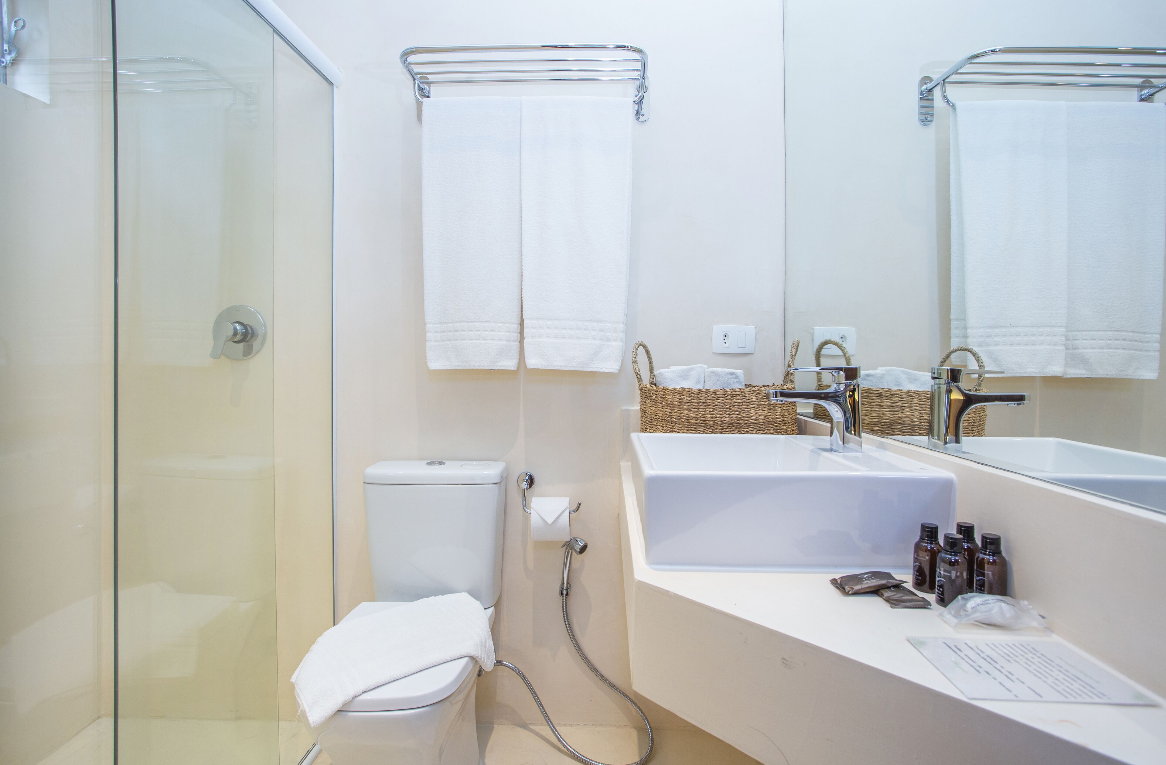 A modern bathroom with a glass shower enclosure, a toilet, a sink with a mirror, and a towel rack.