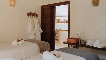 A hotel room with two beds, a bathroom with a sink and mirror, and a door leading to a balcony with a view.